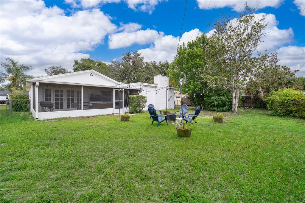 A backyard view of a white house with a screened-in porch and patio furniture — 2464 HUNTERFIELD ROAD, MAITLAND, FL