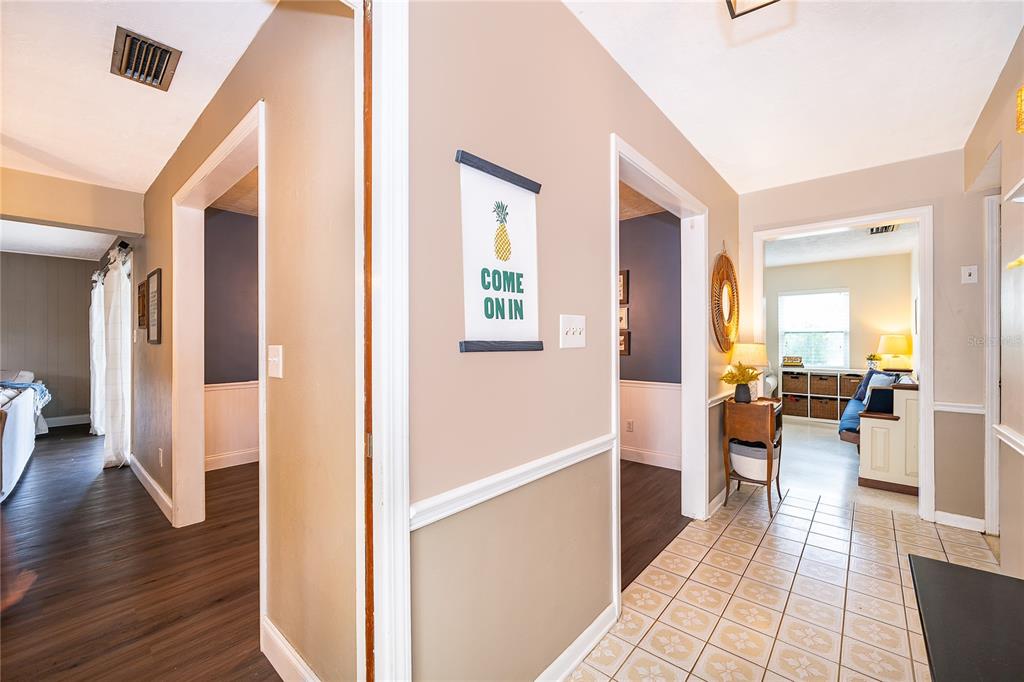 A hallway with tile flooring connects to rooms with wood-look floors and white trim — 2464 HUNTERFIELD ROAD, MAITLAND, FL