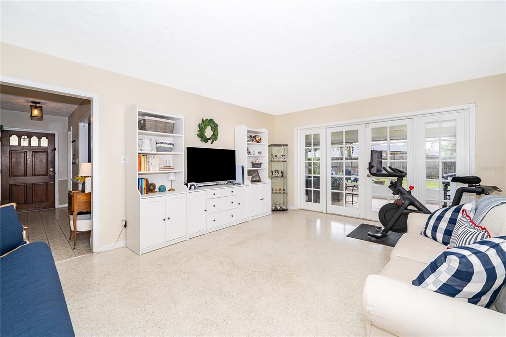 A living room features white built-in shelving, a television, a stationary bike, and glass doors — 2464 HUNTERFIELD ROAD, MAITLAND, FL