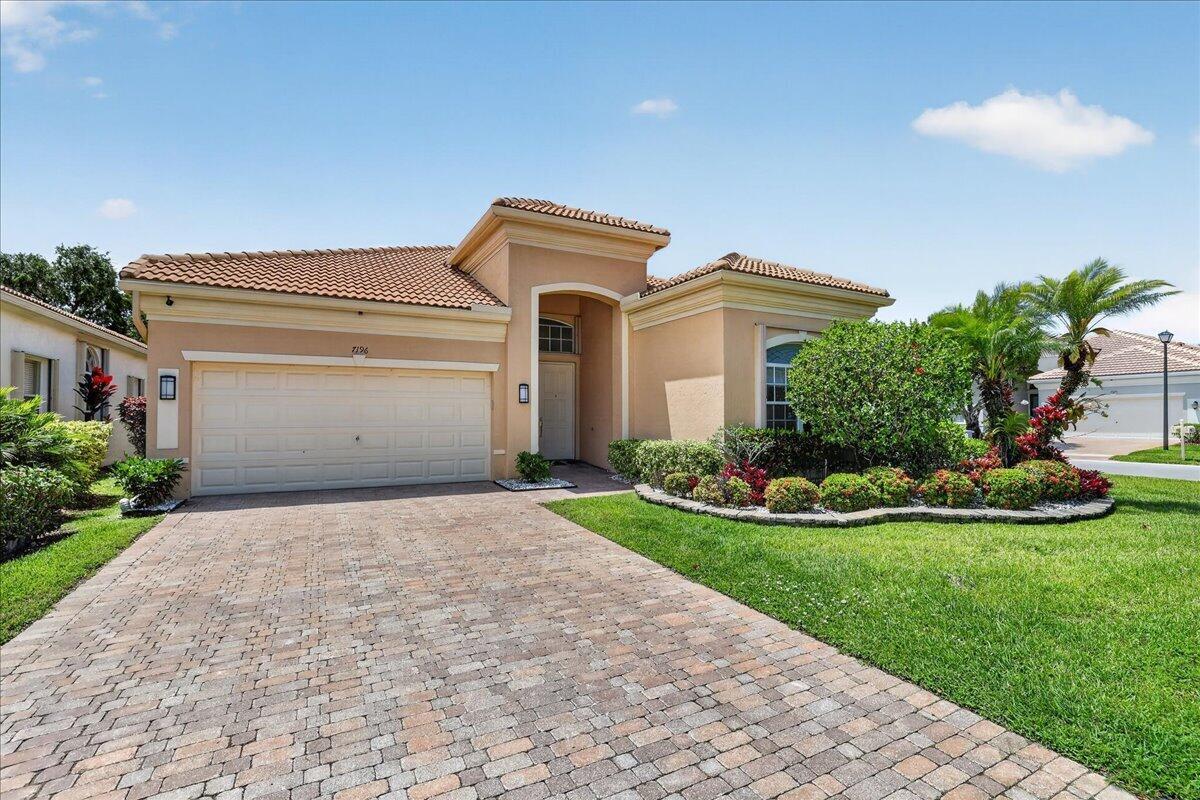 A single-story tan stucco house with a tiled roof and a paved driveway — 7196 Lorenzo Lane, Delray Beach FL 33446, DELRAY BEACH, FL