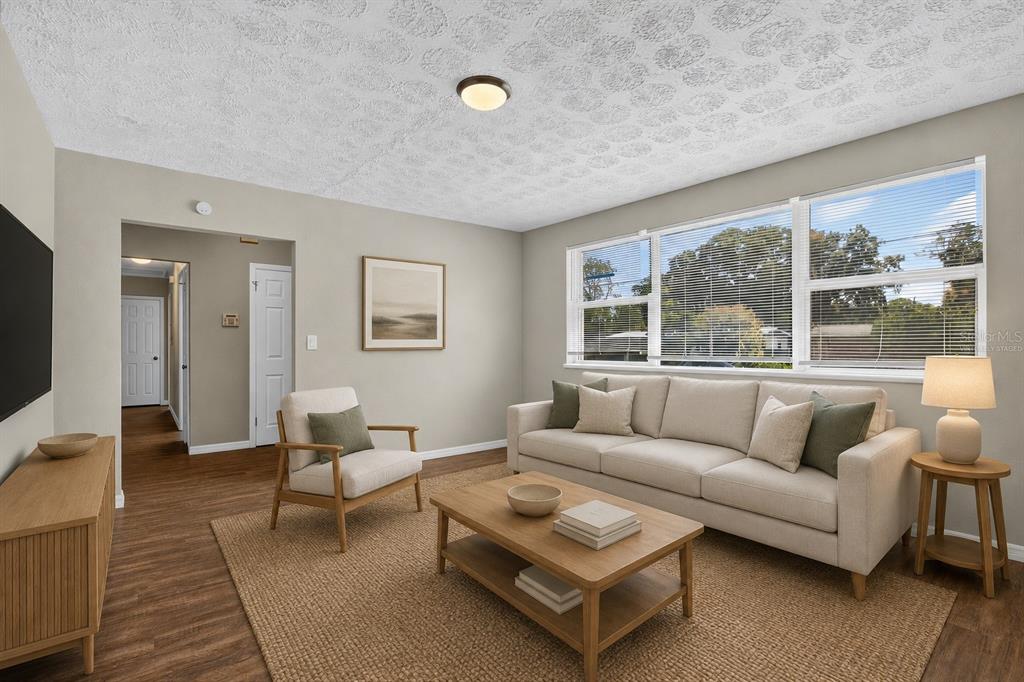 A living room features light-colored walls, wood-look flooring, a beige sofa, and a textured ceiling — 3734 BARMER DRIVE, JACKSONVILLE, FL