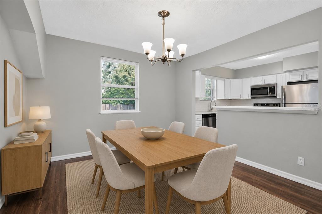 A dining room with a wooden table, six chairs, a sideboard, and an adjacent kitchen — 3734 BARMER DRIVE, JACKSONVILLE, FL