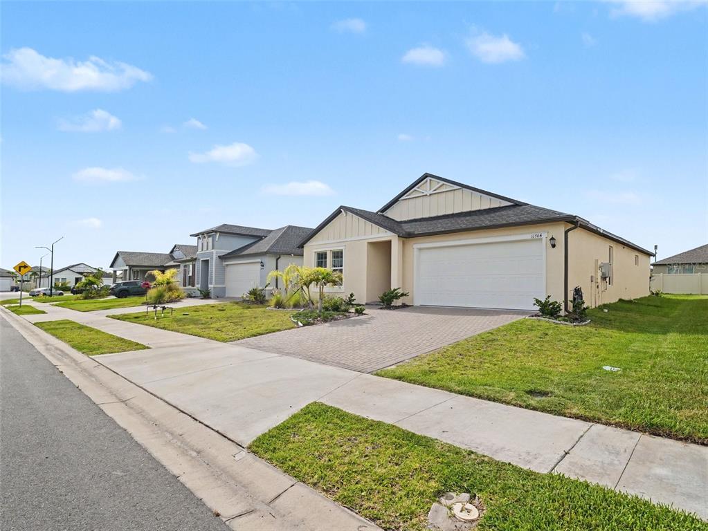 A suburban street view of a single-story house with a paved driveway and garage — 11704 74TH CIR E, PALMETTO, FL