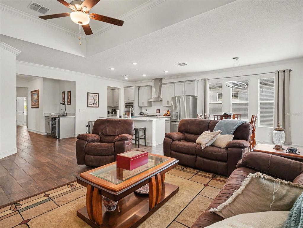An open-concept living room features brown leather furniture, a glass-top coffee table, and a kitchen — 11704 74TH CIR E, PALMETTO, FL