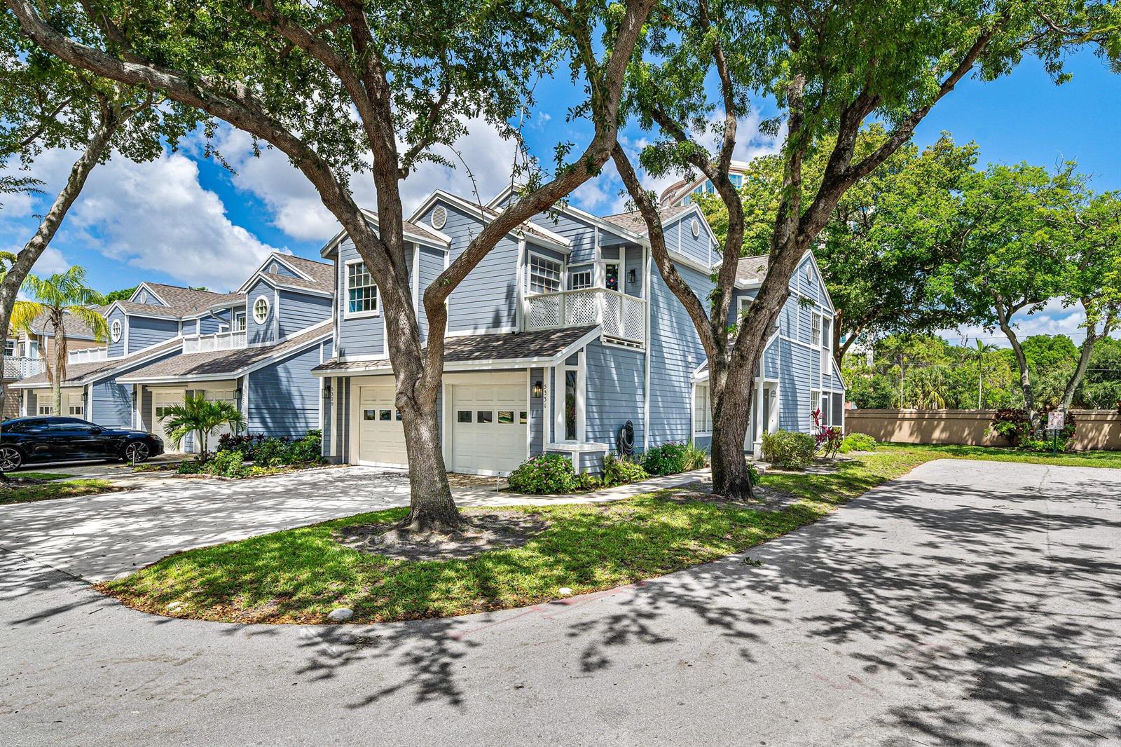 A blue two-story townhouse with a white garage and mature trees in the front yard — 5331 Buckhead Circle # 1030, Boca Raton FL 33486, BOCA RATON, FL