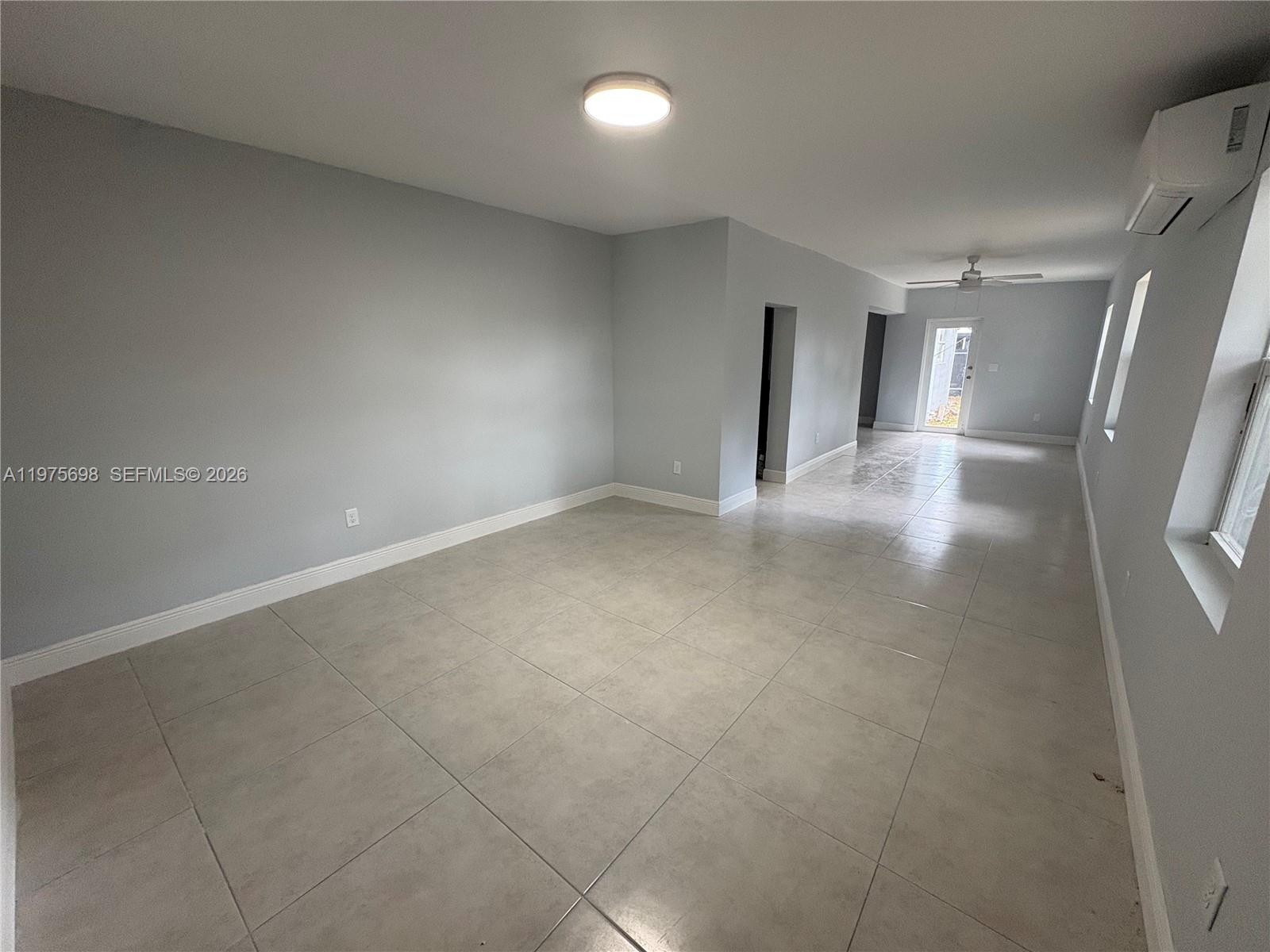 An empty room features light gray walls, large beige floor tiles, and a wall-mounted air conditioner — 3600 SW 32nd Ave, West Park FL 33023, WEST PARK, FL
