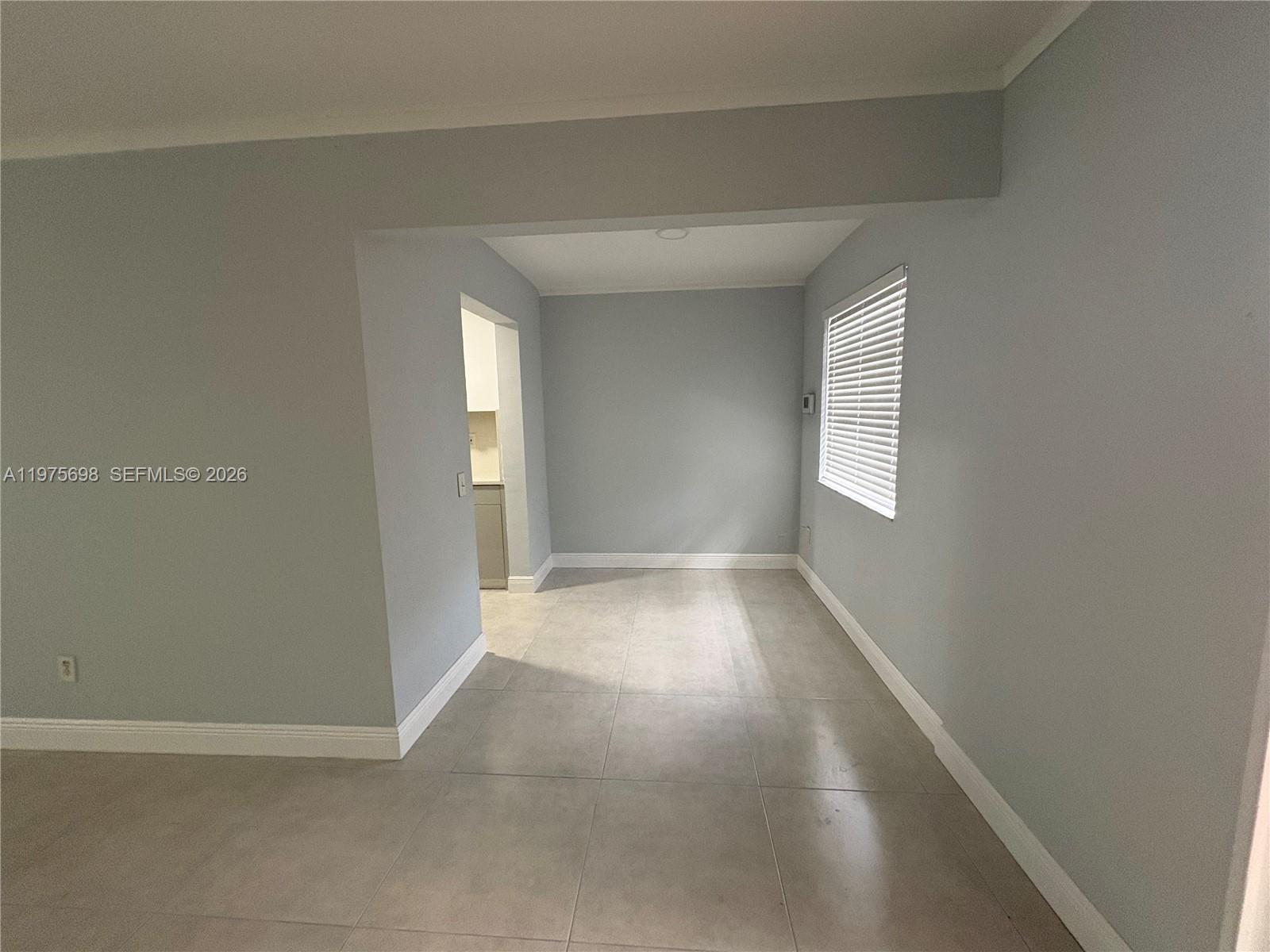 An empty room with light gray walls, large floor tiles, and a single window — 3600 SW 32nd Ave, West Park FL 33023, WEST PARK, FL