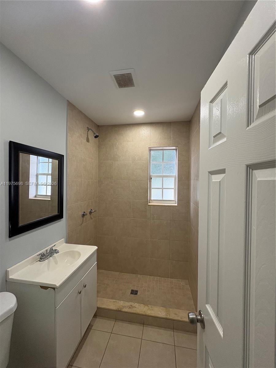 A bathroom features a vanity, a toilet, and a tiled walk-in shower with a window — 3600 SW 32nd Ave, West Park FL 33023, WEST PARK, FL