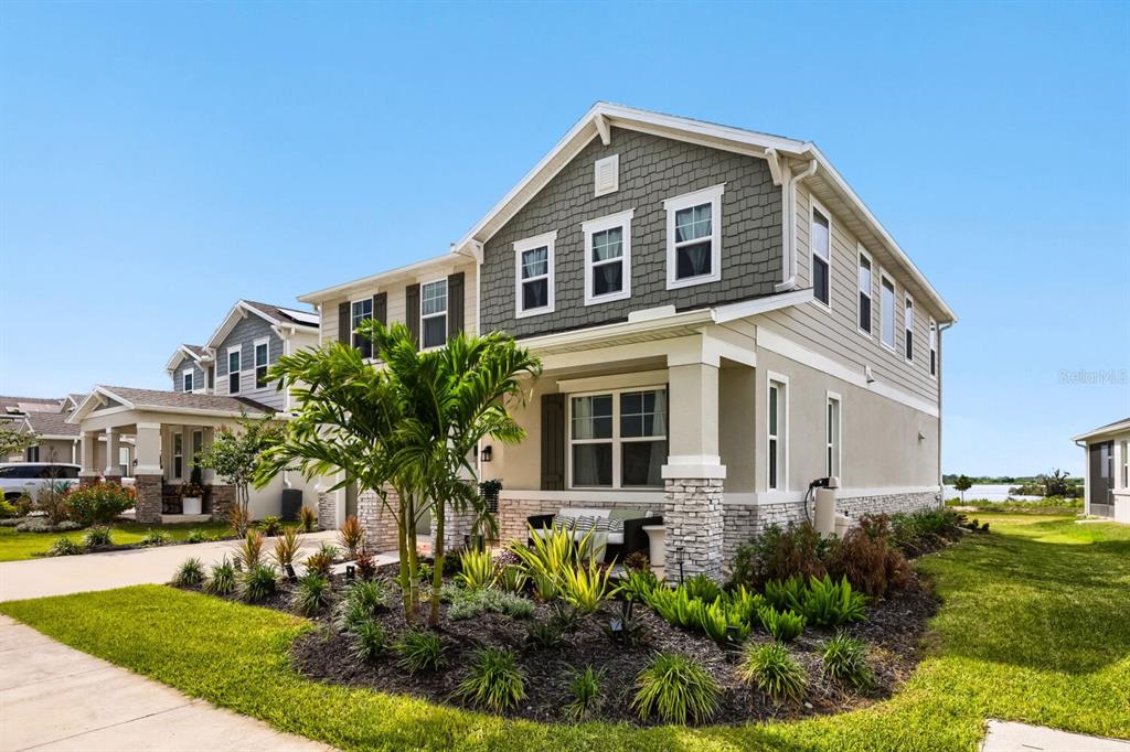 A two-story suburban house features a stone-accented porch, shingle siding, and a landscaped front yard — 900 GRIFFON AVENUE, LAKE ALFRED, FL
