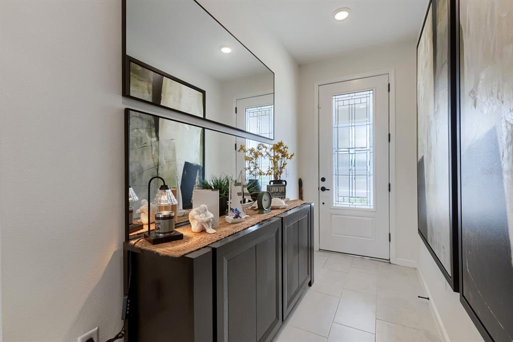 A modern entryway features a dark wood console table, large wall mirrors, and tile flooring — 900 GRIFFON AVENUE, LAKE ALFRED, FL