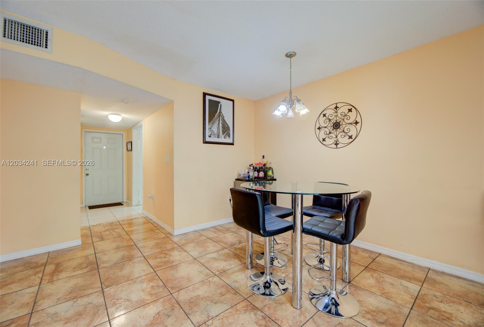 A dining area features a glass-topped table, four black bar stools, and tiled flooring — 7661 NW 38th Ct, Sunrise FL 33351, SUNRISE, FL