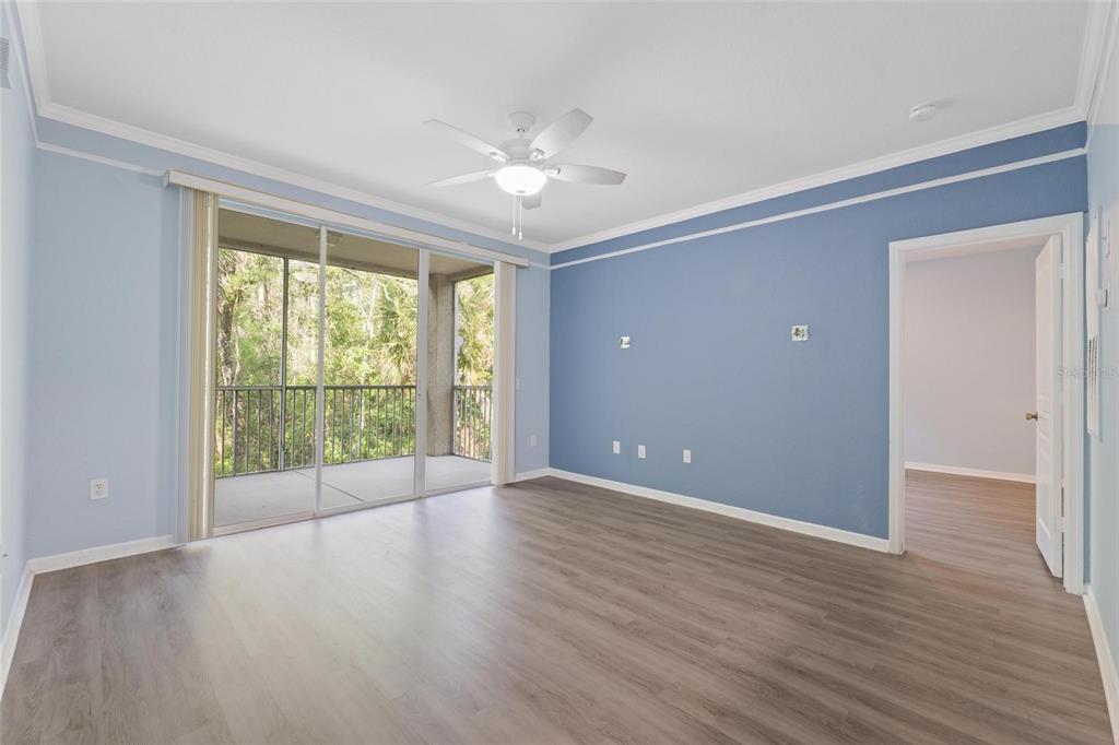 An empty room with blue walls, wood-look flooring, a ceiling fan, and a sliding glass door — 17110 CARRINGTON PARK DRIVE UNIT 832, TAMPA, FL