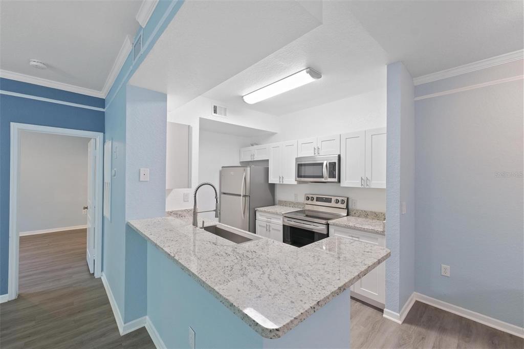 A kitchen with white cabinets, granite countertops, stainless steel appliances, and light blue walls — 17110 CARRINGTON PARK DRIVE UNIT 832, TAMPA, FL