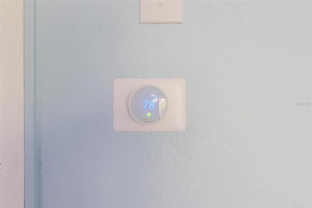 A Nest smart thermostat is mounted on a light blue wall — 17110 CARRINGTON PARK DRIVE UNIT 832, TAMPA, FL
