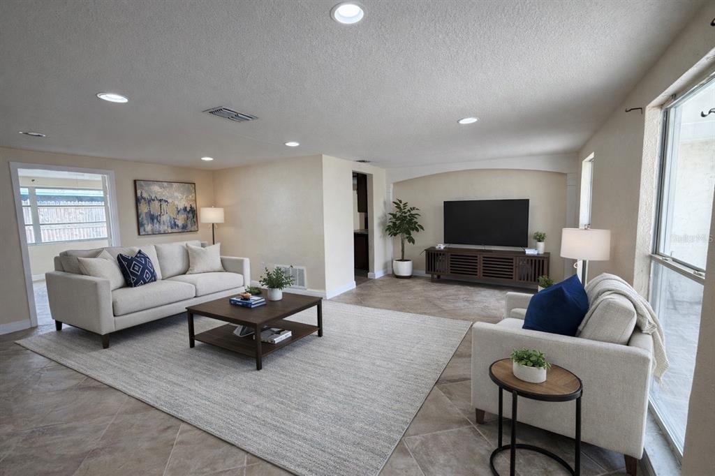 A living room features a beige sofa, armchair, coffee table, and television on a tiled floor — 3628 LANDALE DRIVE, HOLIDAY, FL