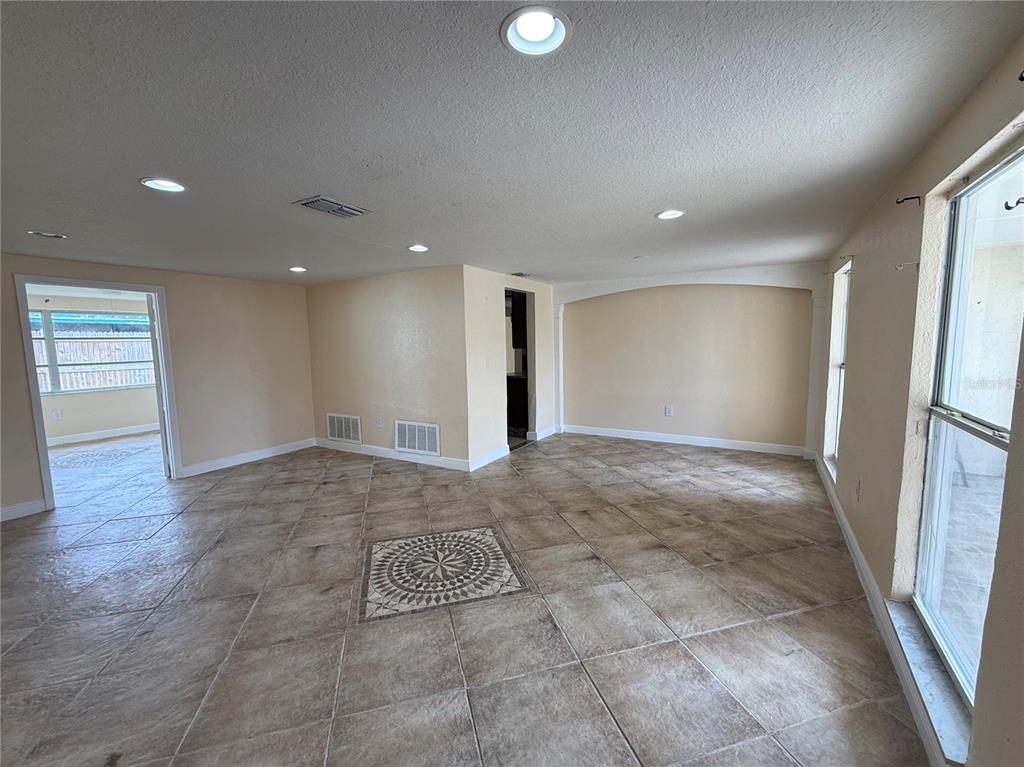 A spacious room with light-colored tile flooring, recessed lighting, and a decorative tile inlay — 3628 LANDALE DRIVE, HOLIDAY, FL