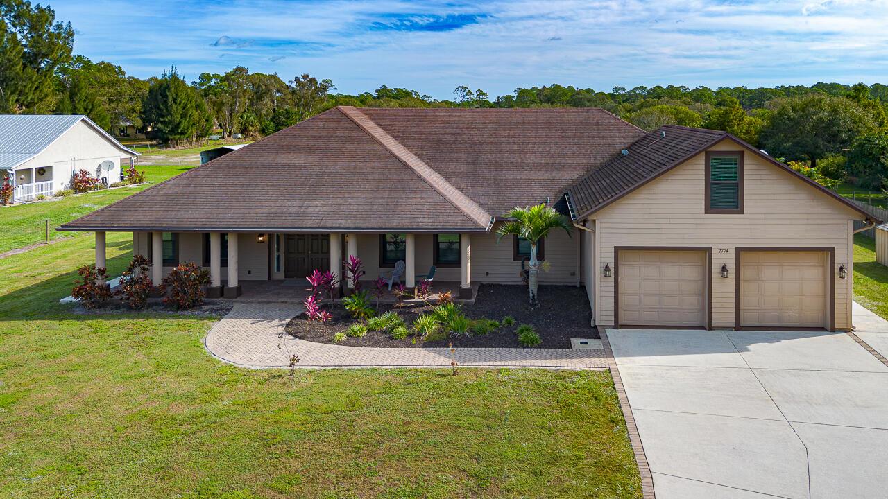 An aerial view of a single-story house with a brown roof and attached two-car garage — 2774 Gentile Road, Fort Pierce FL 34945, FORT PIERCE, FL