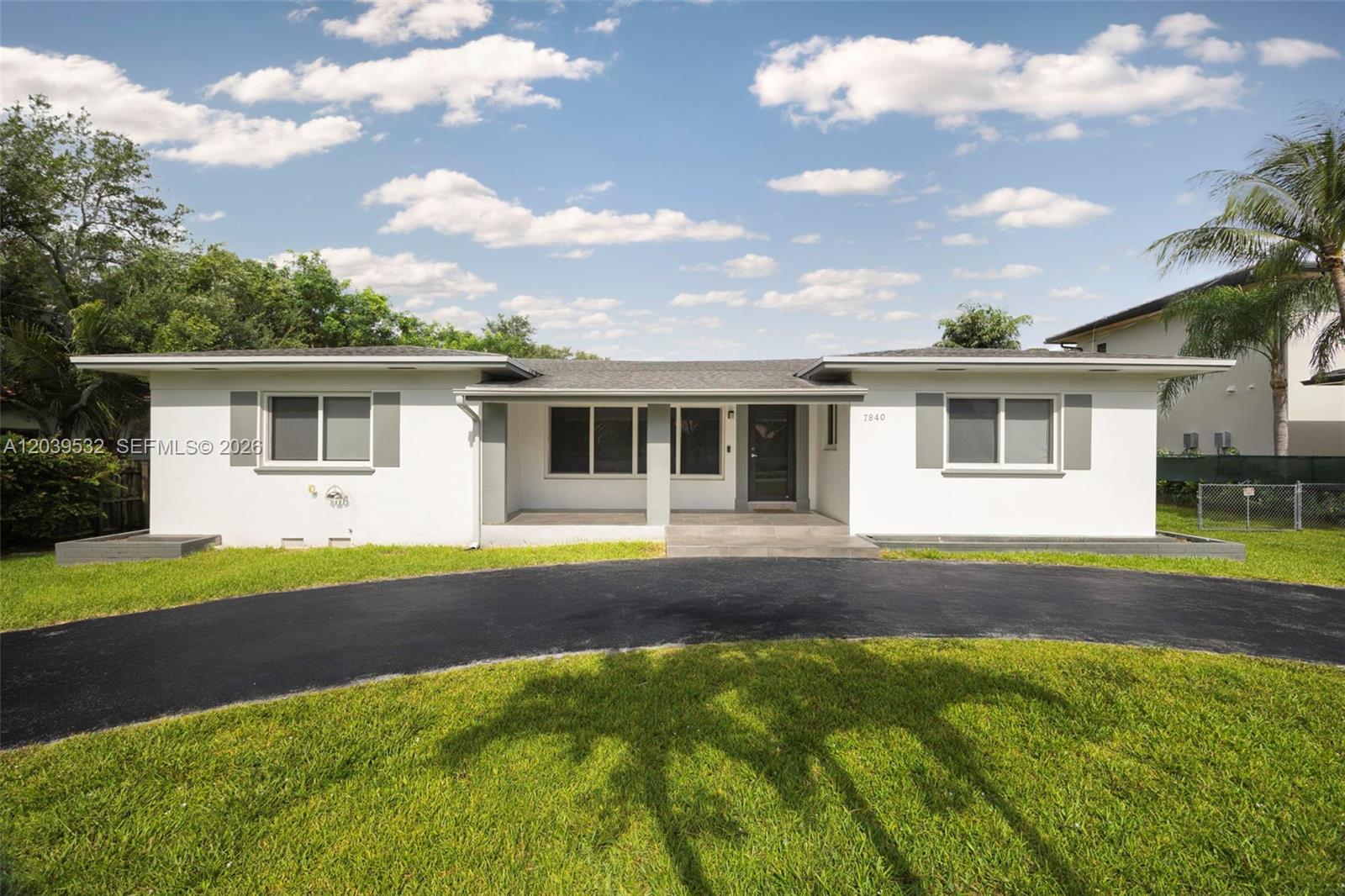 A single-story white house features a dark driveway and a covered front porch entrance — 7840 SW 71st Ave, Miami FL 33143, MIAMI, FL