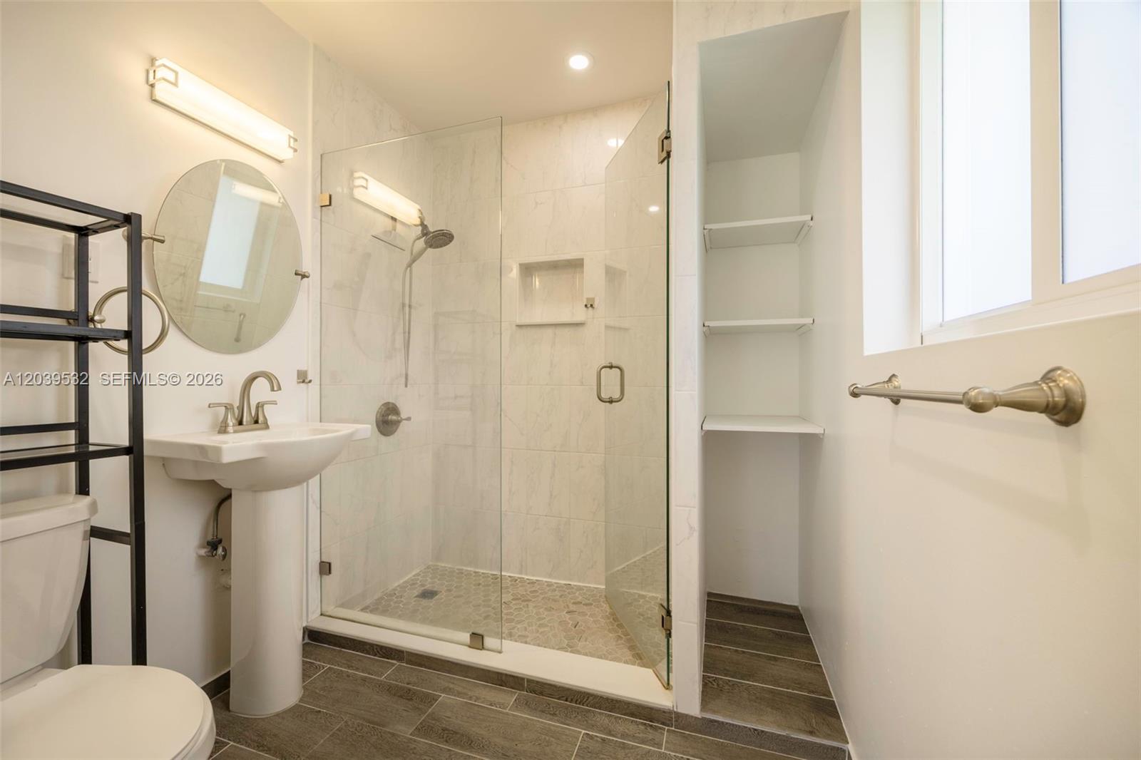 A bathroom features a pedestal sink, a glass-enclosed shower, and built-in wall shelving — 7840 SW 71st Ave, Miami FL 33143, MIAMI, FL