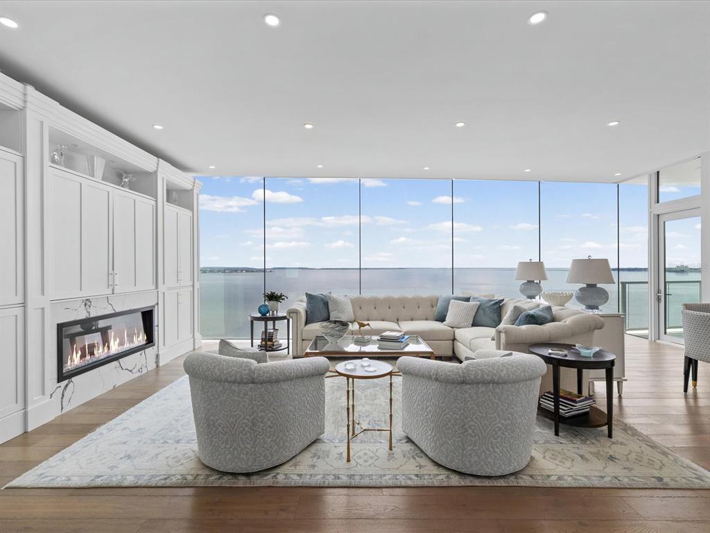 A living room features a fireplace, built-in cabinetry, and floor-to-ceiling windows overlooking the water — 2619 BAYSHORE BOULEVARD UNIT 900, TAMPA, FL