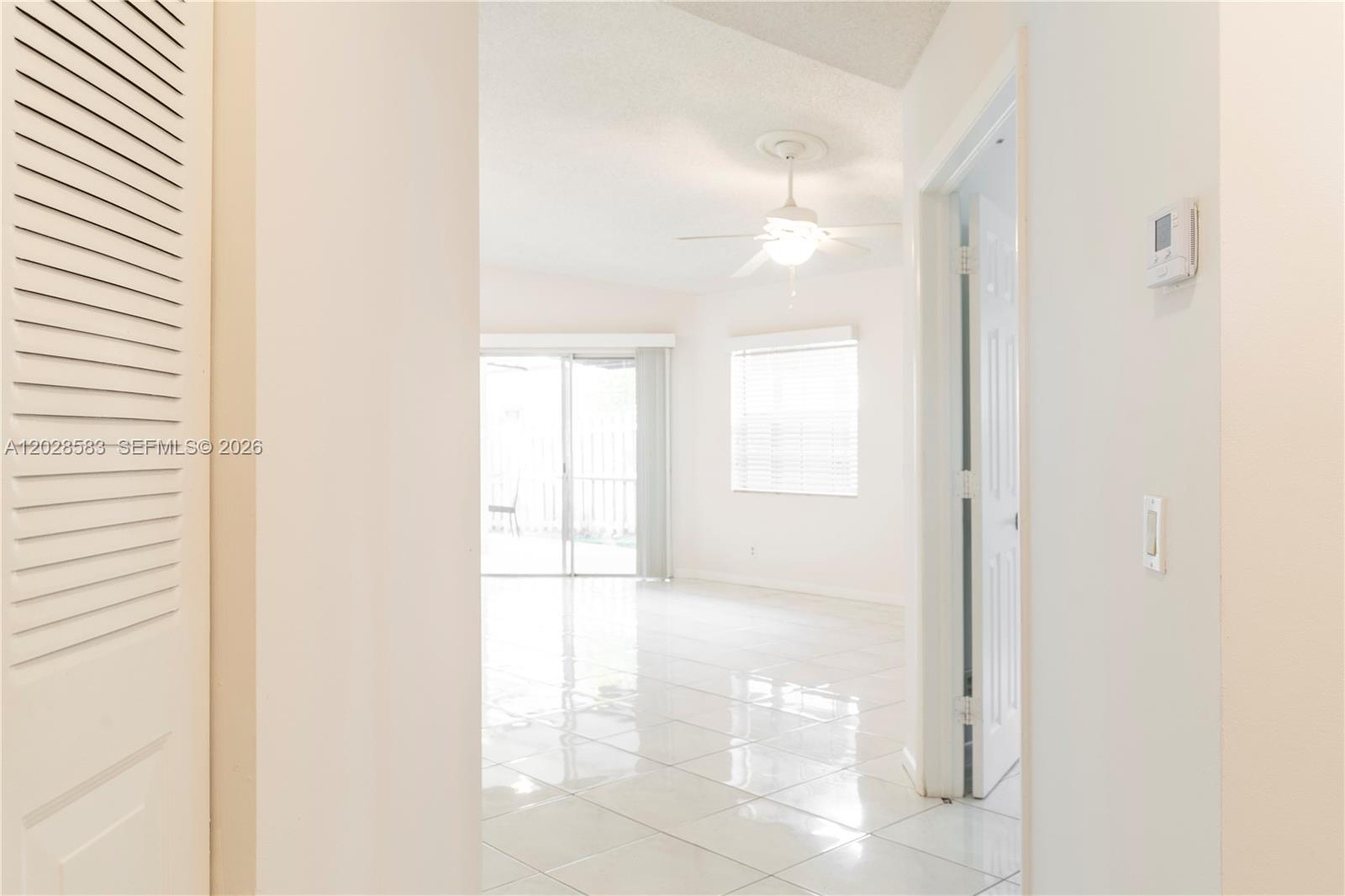 A bright room with white tile floors, a ceiling fan, and sliding glass patio doors — 1341 Seagrape Cir, Weston FL 33326, WESTON, FL