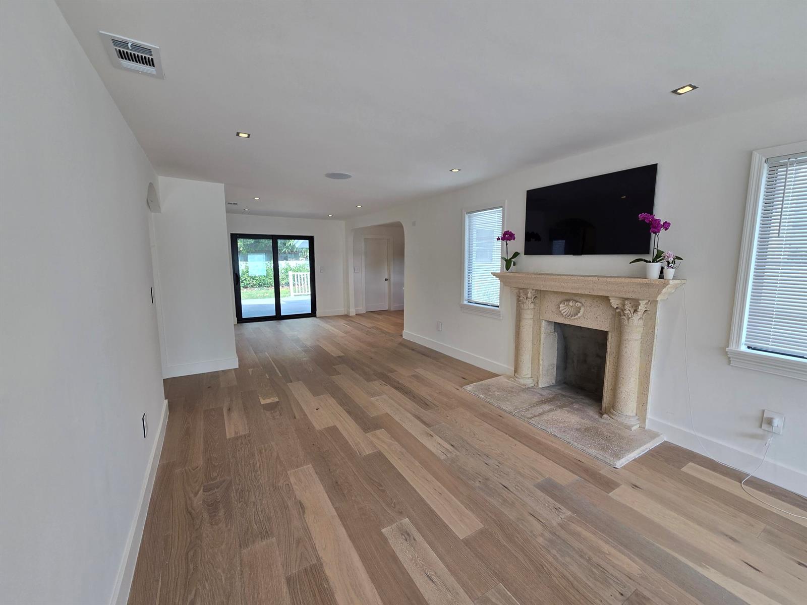 A living room features light wood flooring, a stone fireplace, and a wall-mounted television — 3809 S Olive Avenue, West Palm Beach FL 33405, WEST PALM BEACH, FL