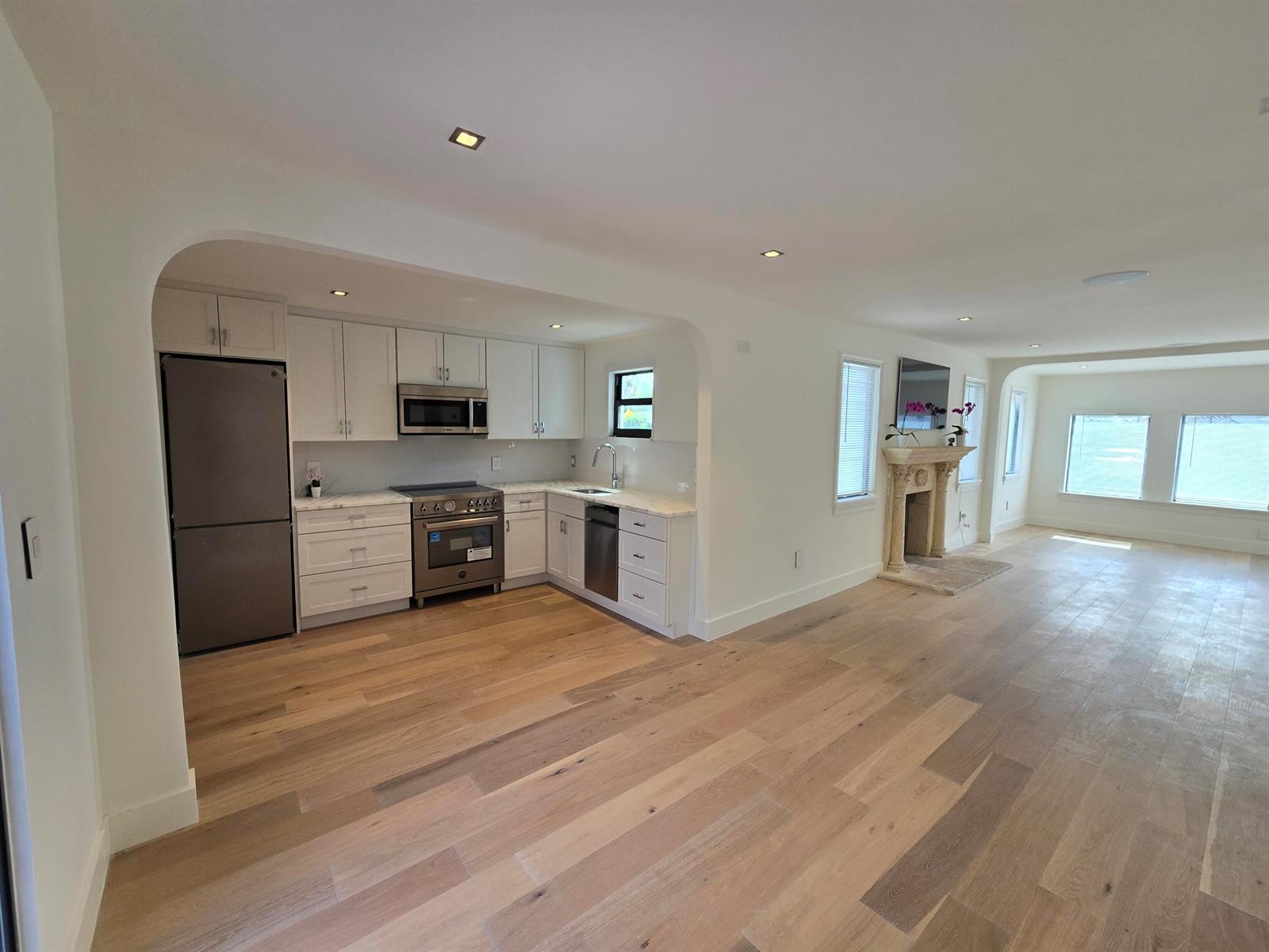 A kitchen with white cabinets and stainless steel appliances opens into a living area — 3809 S Olive Avenue, West Palm Beach FL 33405, WEST PALM BEACH, FL