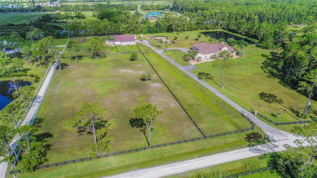 An aerial view shows a large house, a barn, and fenced pastures on a rural property — 260 SPRING FOREST DRIVE, NEW SMYRNA BEACH, FL