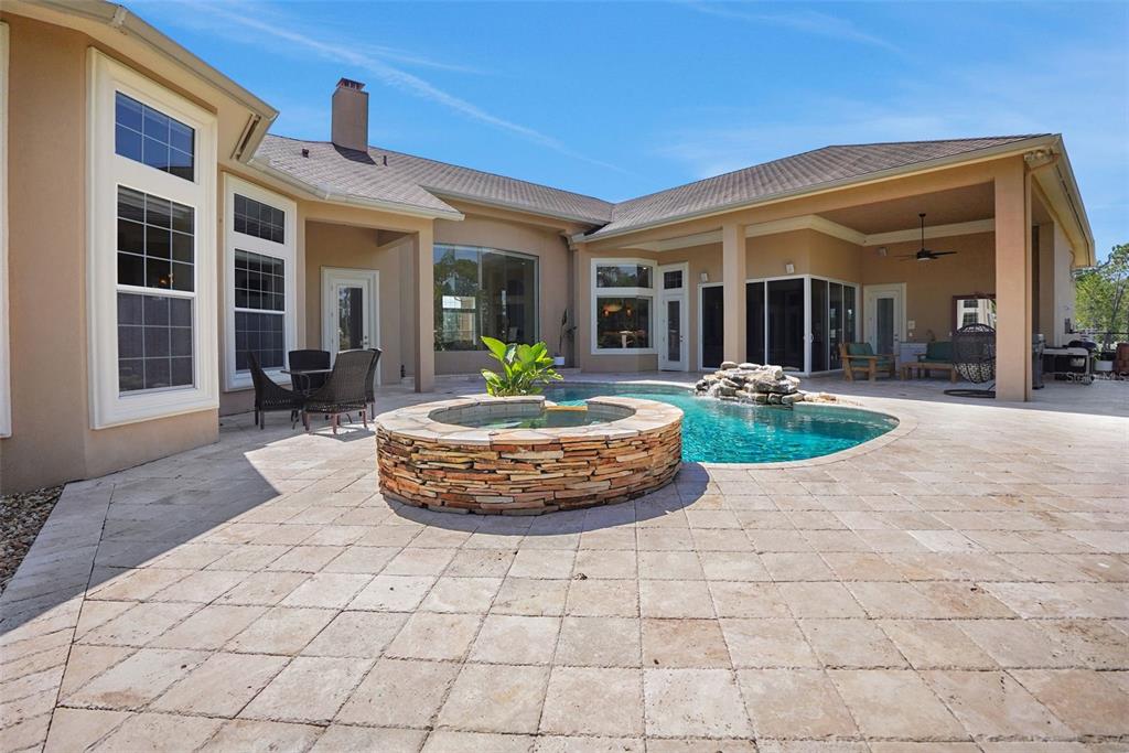 A backyard patio features a stone-clad hot tub, a swimming pool, and a covered lanai — 260 SPRING FOREST DRIVE, NEW SMYRNA BEACH, FL