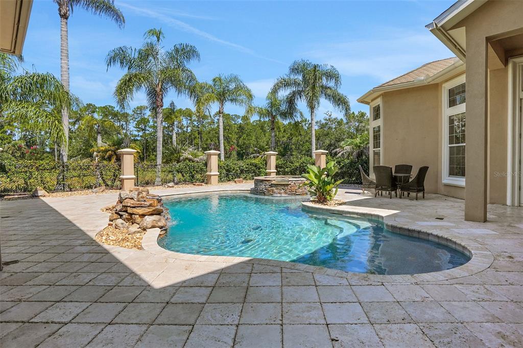 A backyard patio features a swimming pool with a rock waterfall and a stone spa — 260 SPRING FOREST DRIVE, NEW SMYRNA BEACH, FL