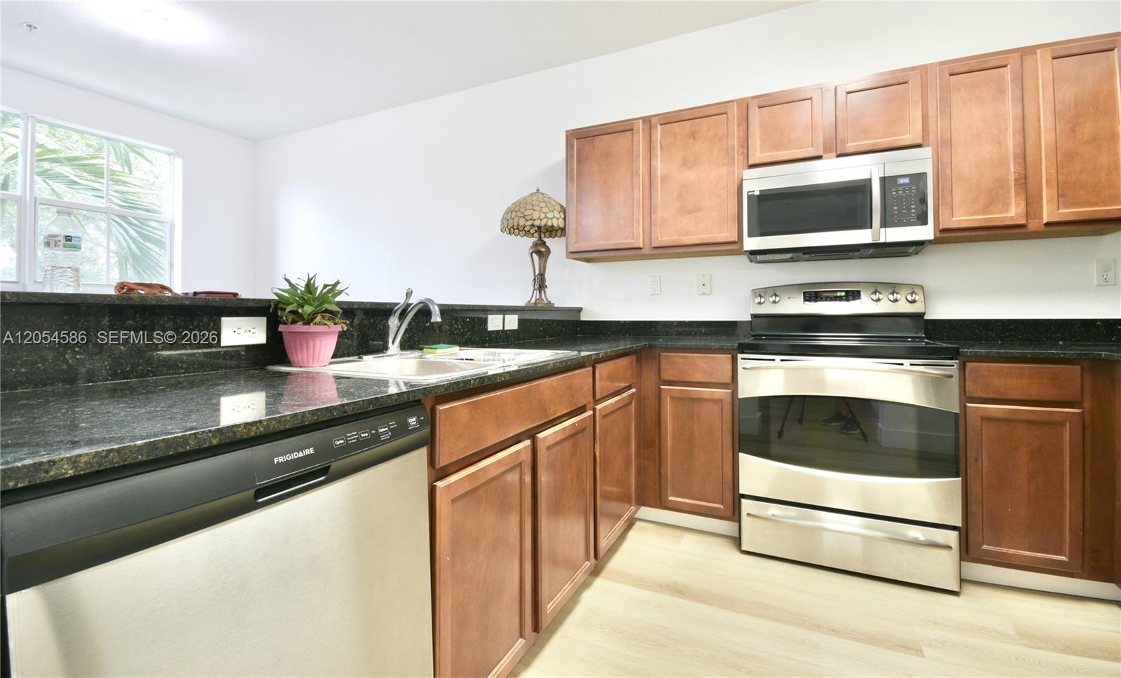 A kitchen features wood cabinets, stainless steel appliances, and dark granite countertops — 10870 NW 88th Ter # 222, Doral FL 33178, DORAL, FL