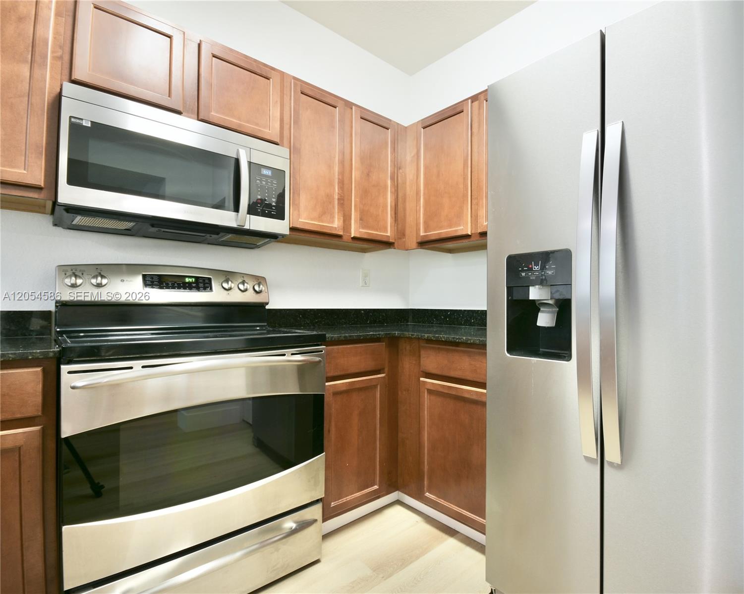 A kitchen features stainless steel appliances, dark wood cabinets, and black granite countertops — 10870 NW 88th Ter # 222, Doral FL 33178, DORAL, FL