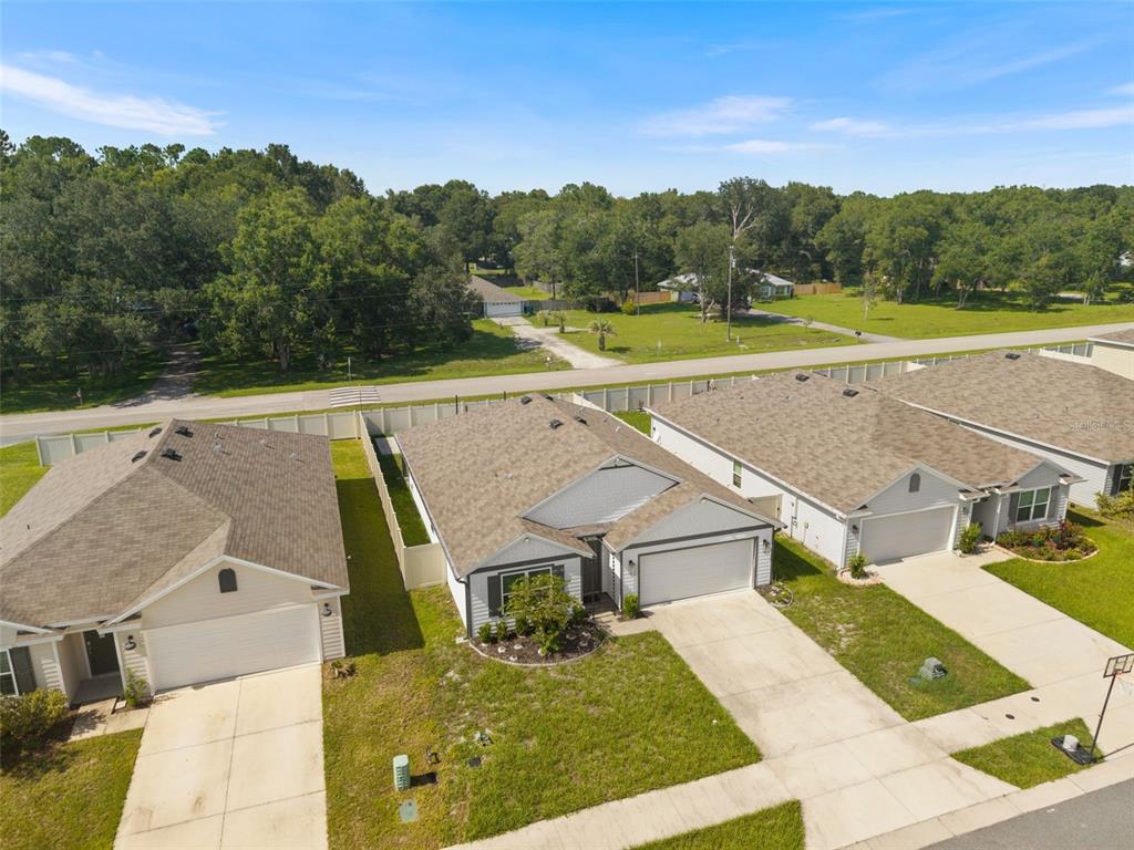 An aerial view shows three suburban houses with driveways and lawns near a wooded area — 24596 NW 23RD LANE, NEWBERRY, FL