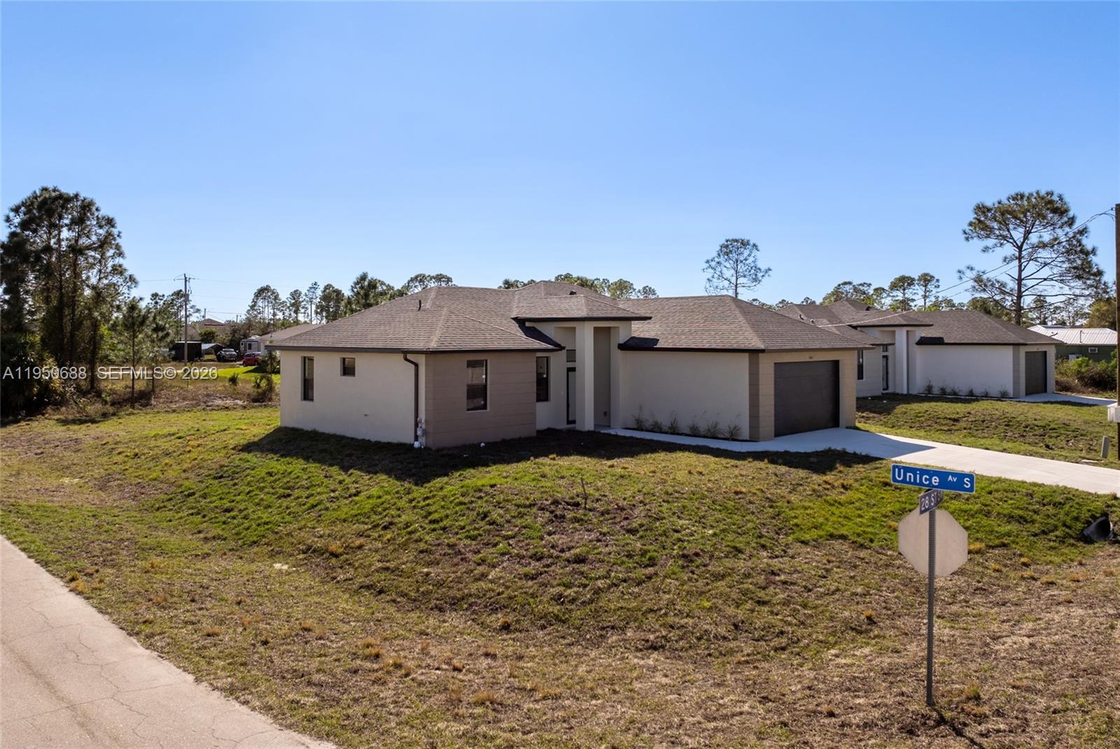 A newly constructed single-story house with a two-car garage sits on a grassy corner lot — 3601 28th St SW, Lehigh Acres FL 33976, LEHIGH ACRES, FL