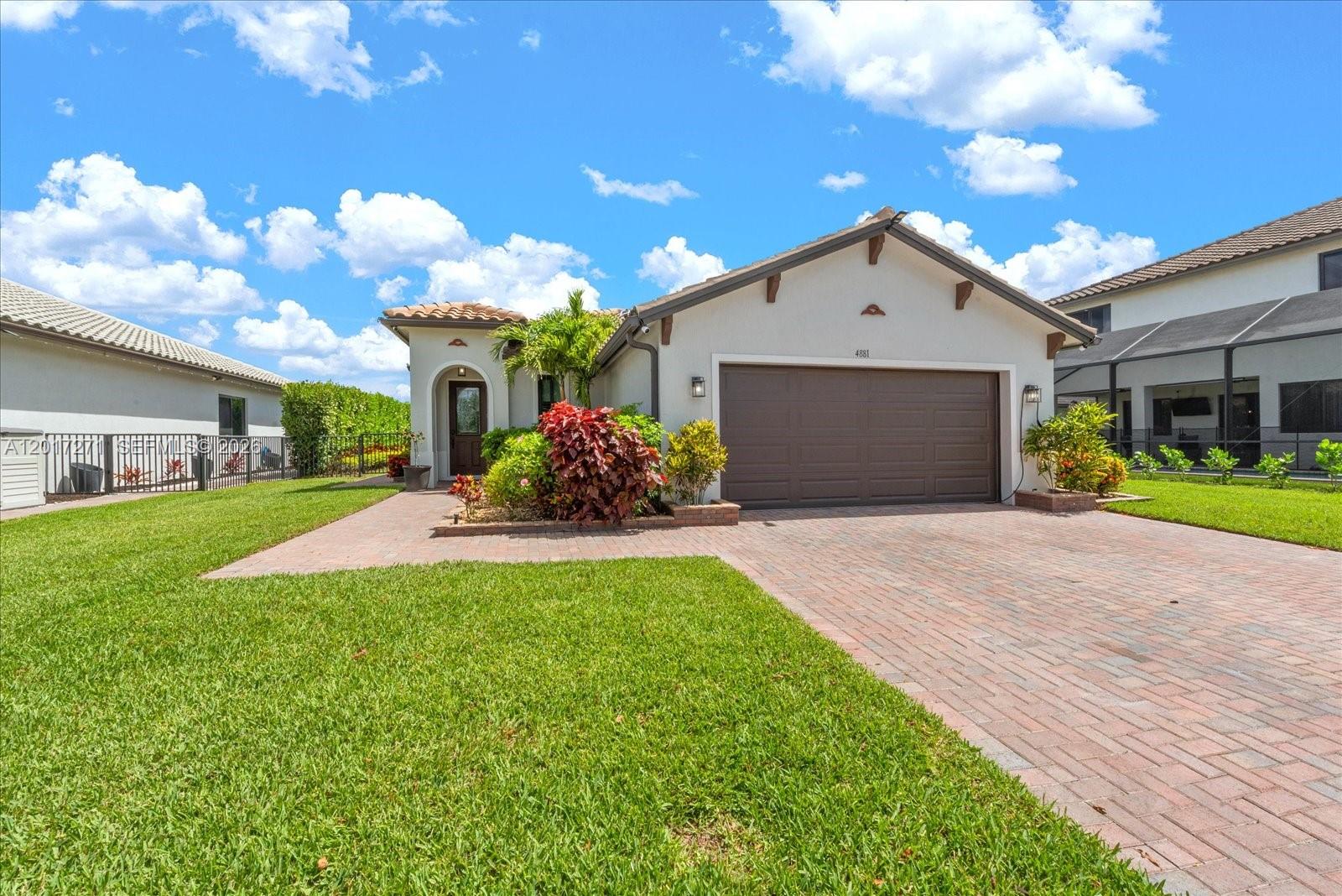 A single-story house features a brick driveway, a two-car garage, and a landscaped front yard — 4881 Iron Horse Way, Ave Maria FL 34142, AVE MARIA, FL