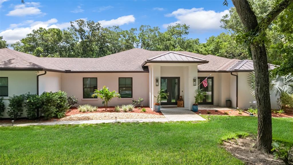 A single-story house with a white exterior, dark roof, and a central covered entryway — 14 MERIDIAN HOME LANE, PALM COAST, FL