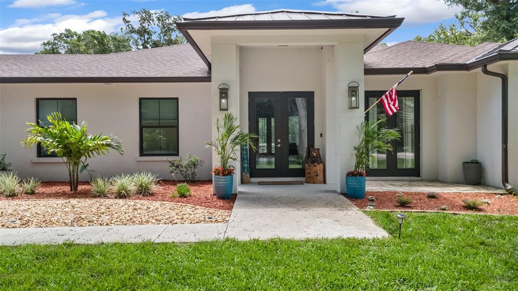 The exterior of a single-story house features a white facade, dark-framed windows, and a double-door entrance — 14 MERIDIAN HOME LANE, PALM COAST, FL