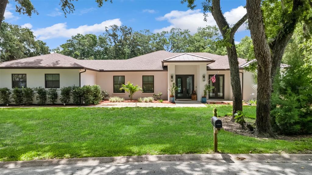 A single-story white house with a dark roof, black-framed windows, and a central entryway — 14 MERIDIAN HOME LANE, PALM COAST, FL