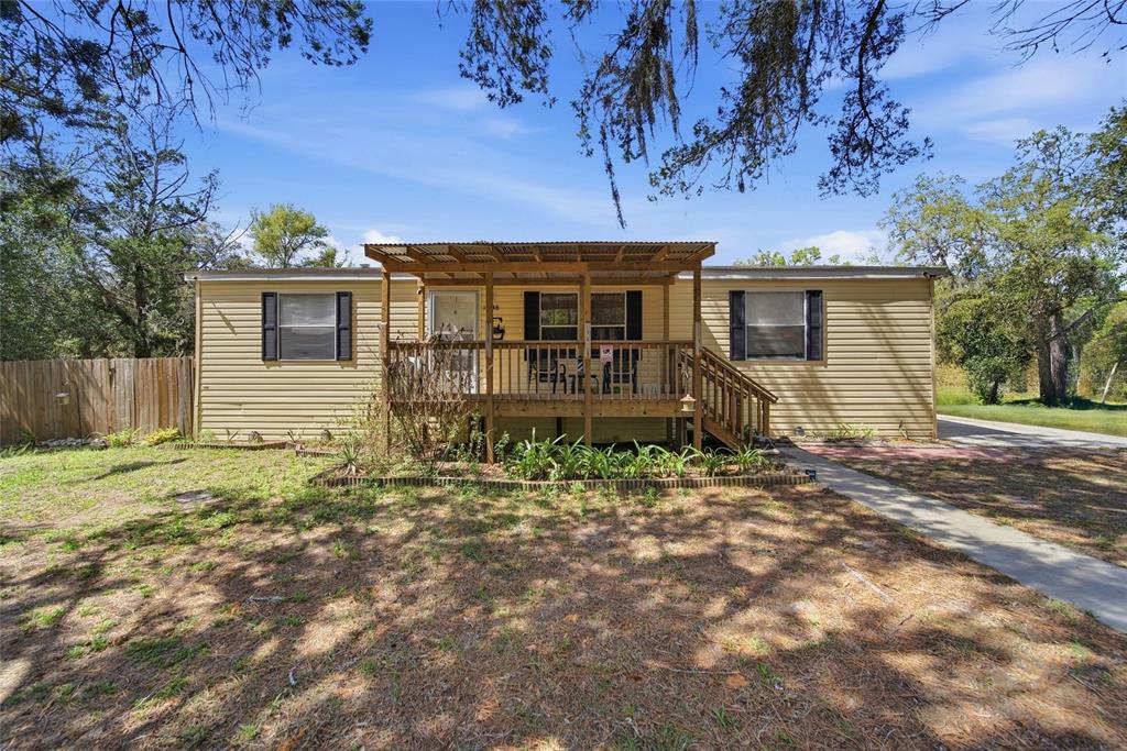 A light-colored mobile home sits on a wooded lot with a dirt driveway — 12148 RUTHERFORD LANE, HUDSON, FL