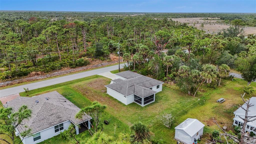 An aerial view shows two single-story houses with gray roofs surrounded by trees and grass — 5400 JENNINGS BOULEVARD, PORT CHARLOTTE, FL