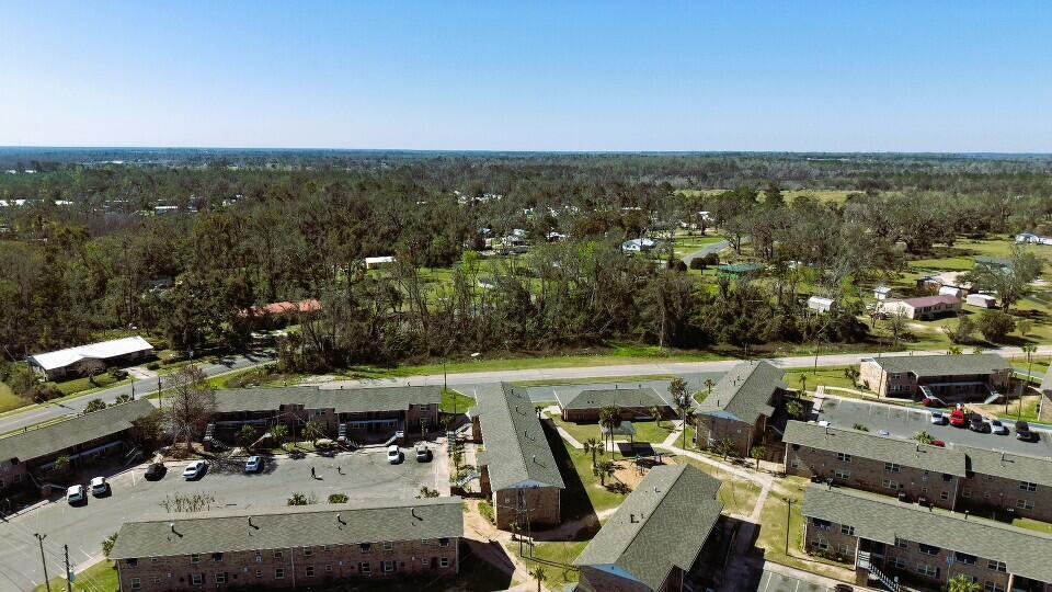 An aerial view shows several multi-story apartment buildings with green roofs and surrounding parking lots — Lot 7 SW Bum Gardener Drive, FL 32340, FL