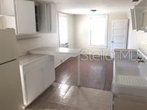 A kitchen features white cabinets, a small breakfast bar, and a window overlooking a room — 114 N CHESTER STREET, LEESBURG, FL