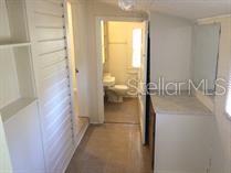 A hallway with white walls leads to a bathroom with a toilet and vanity — 114 N CHESTER STREET, LEESBURG, FL