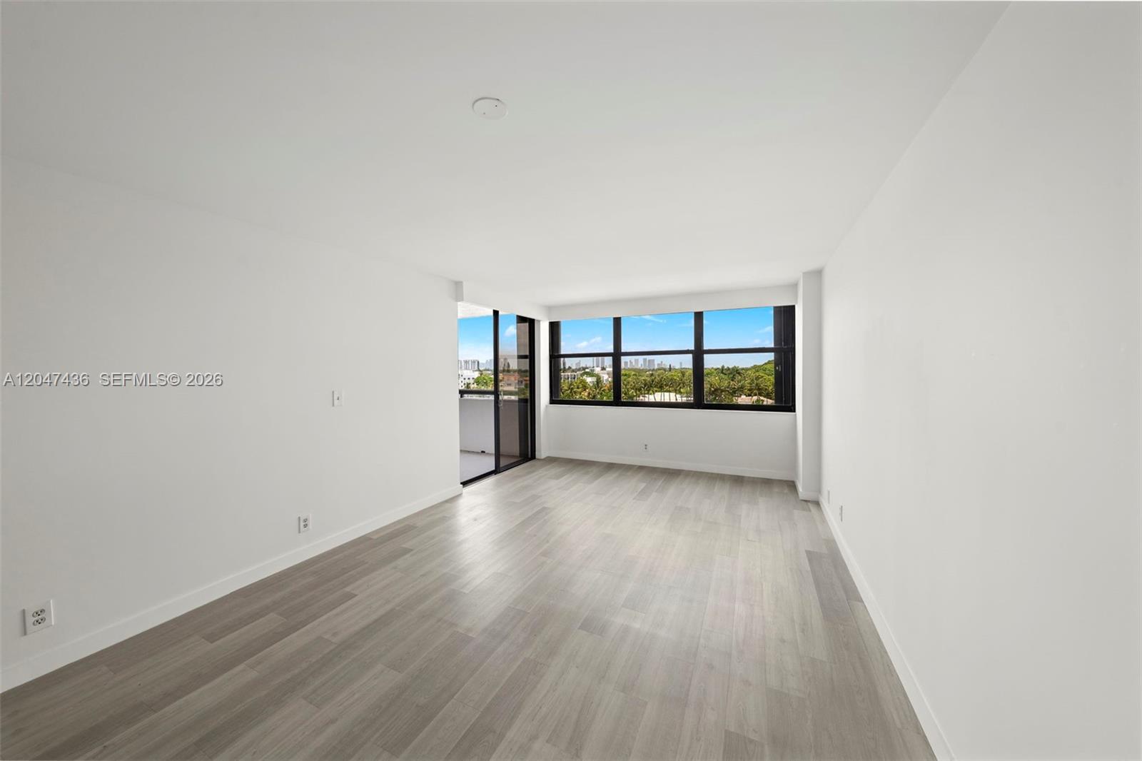 An empty room features light wood-look flooring, white walls, and a large window with views — 2555 Collins Ave # 706, Miami Beach FL 33140, MIAMI BEACH, FL