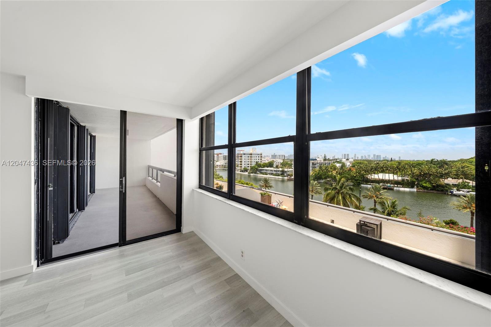 A room with light wood-look flooring, large windows, and a sliding door to a balcony — 2555 Collins Ave # 706, Miami Beach FL 33140, MIAMI BEACH, FL