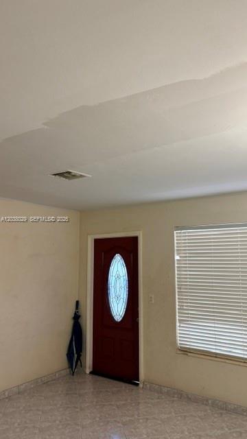 A room with tiled floors, a red front door, and a water stain on the ceiling — 6833 SW 20th St, Miramar FL 33023, MIRAMAR, FL