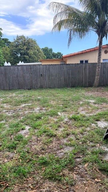 A backyard features a patch of grass and dirt enclosed by a wooden fence — 6833 SW 20th St, Miramar FL 33023, MIRAMAR, FL