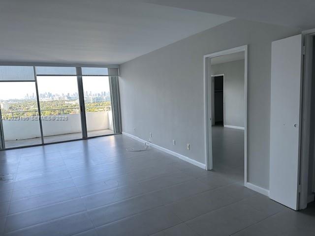 An empty living room features light gray tile flooring, white walls, and a balcony view — 5161 Collins Ave # 1709, Miami Beach FL 33140, MIAMI BEACH, FL