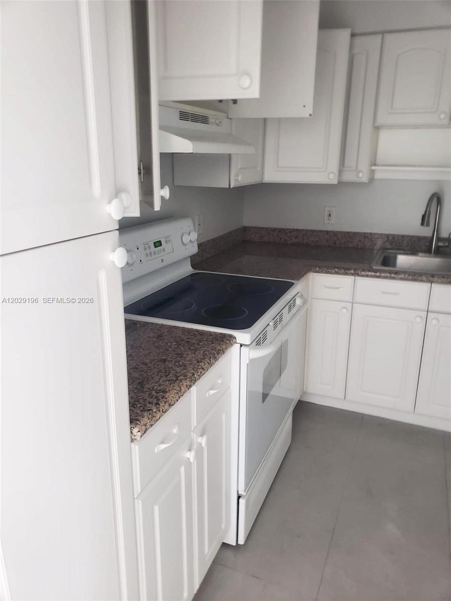 A kitchen features white cabinets, a speckled countertop, and a white electric stove — 5161 Collins Ave # 1709, Miami Beach FL 33140, MIAMI BEACH, FL