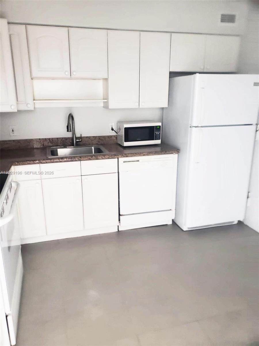 A kitchen features white cabinets, a stainless steel sink, a microwave, and a white refrigerator — 5161 Collins Ave # 1709, Miami Beach FL 33140, MIAMI BEACH, FL